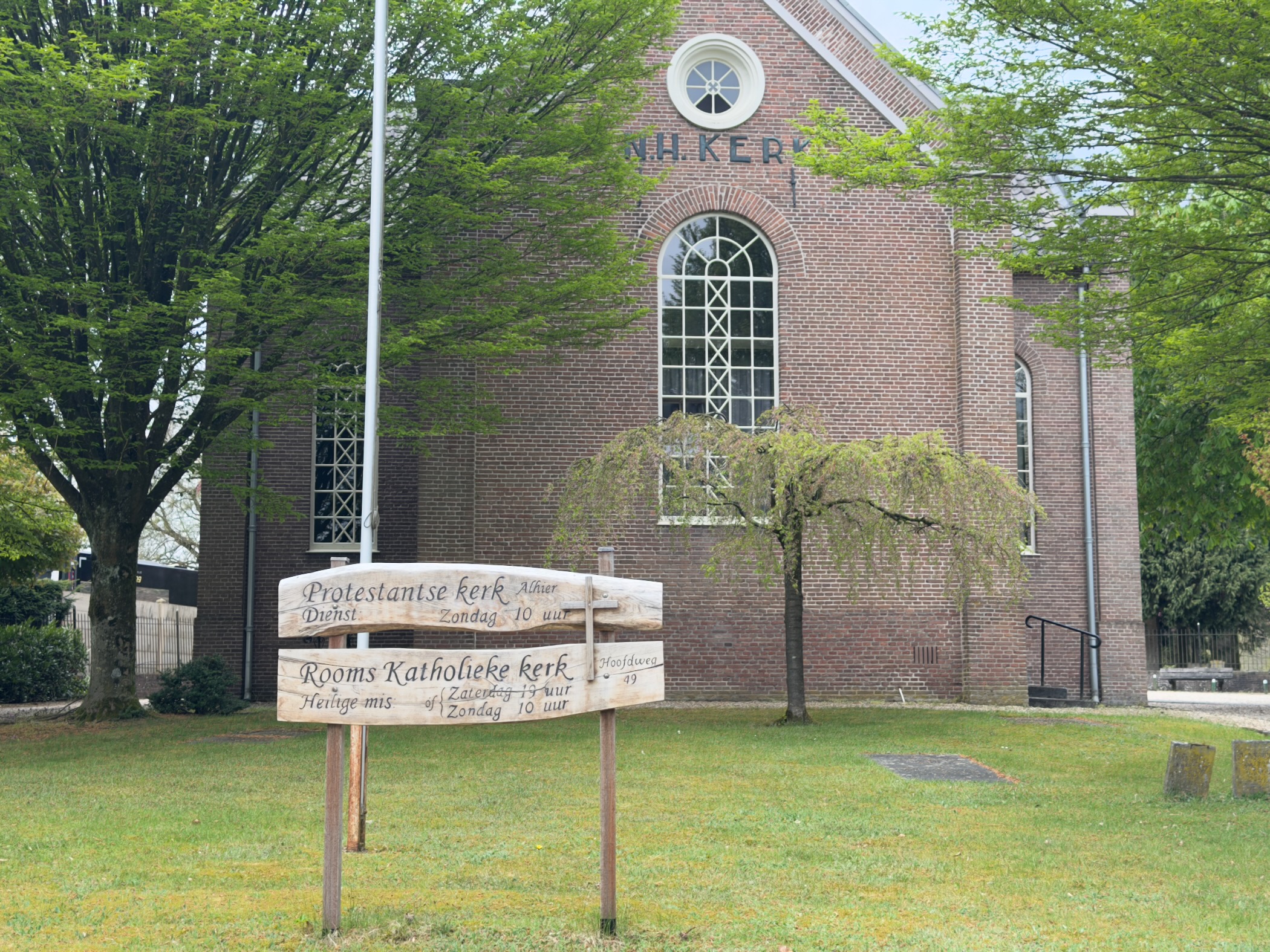 Protestant church (N.H. Kerk) in Loenen with a wooden signboard showing service times