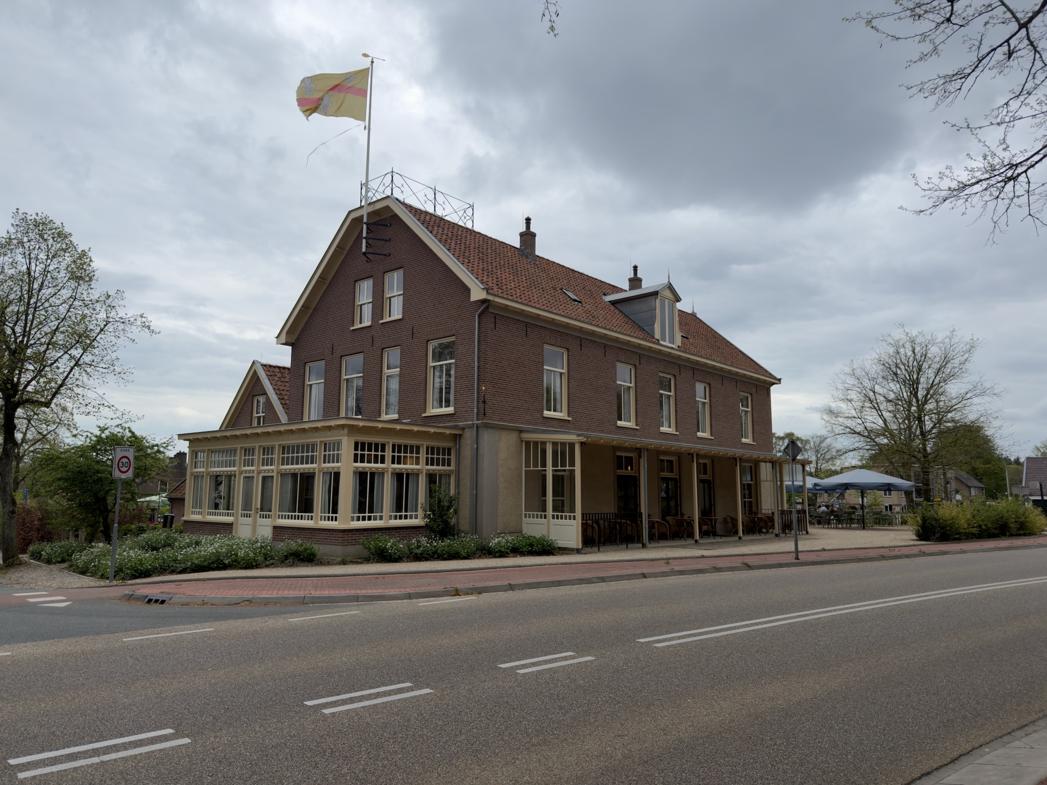 Brick hotel-café building in Loenen with an orange-yellow flag flying from a pole