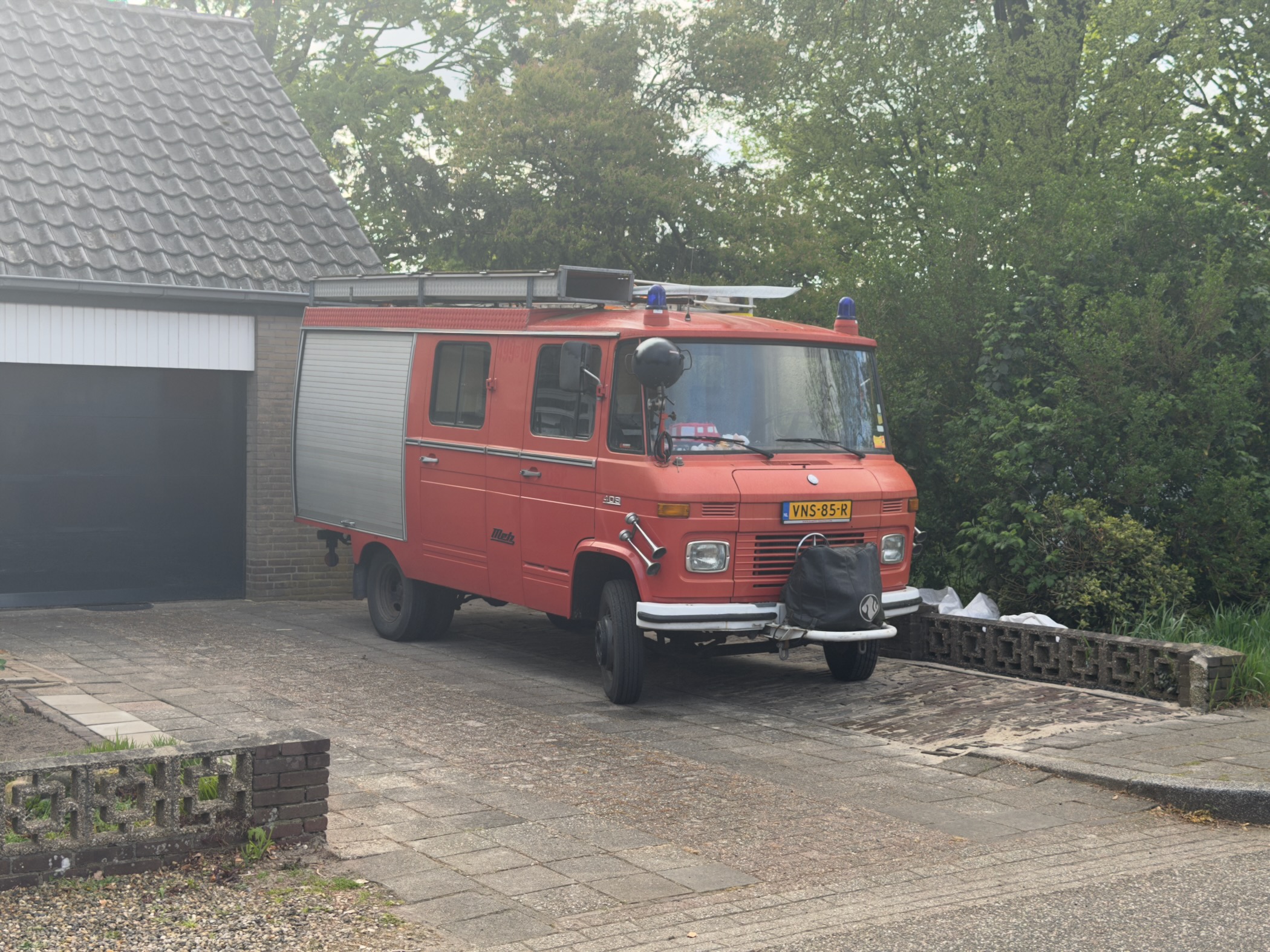 Vintage red Mercedes-Benz fire truck converted into a camper parked on a driveway