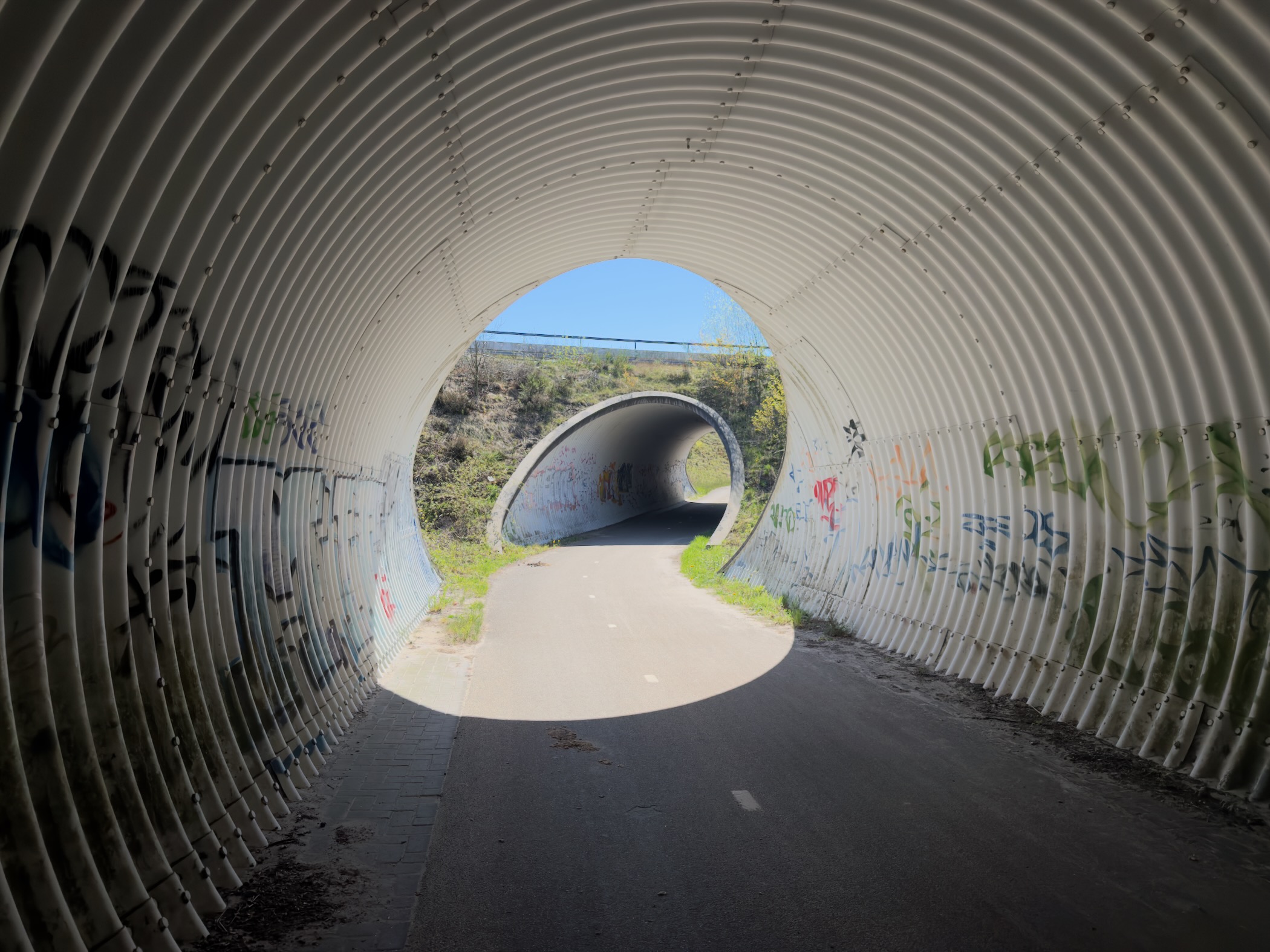 Graffiti-covered pedestrian tunnel leading onward to a second tunnel