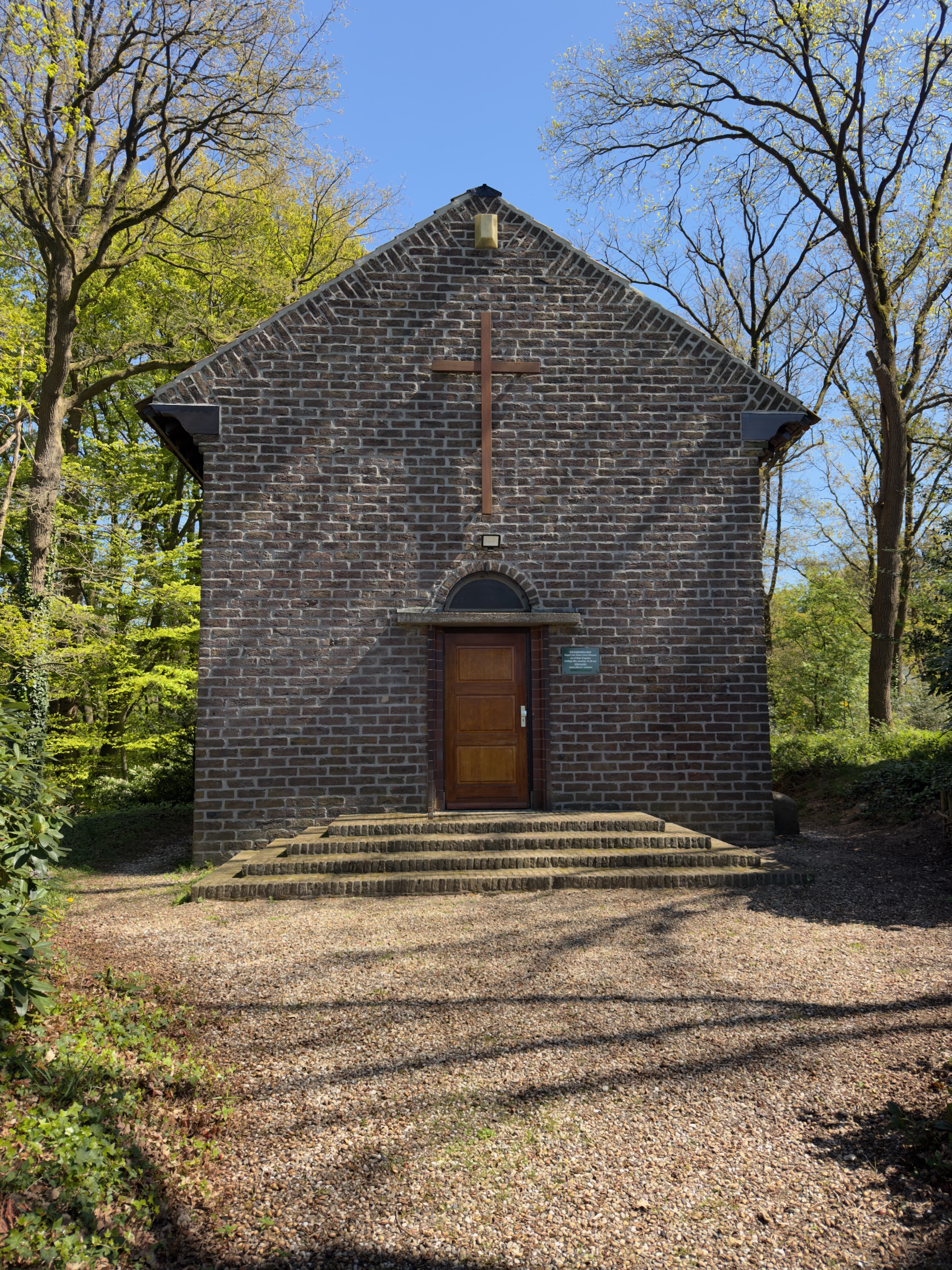 Small brick chapel with a cross above the door set in the woods