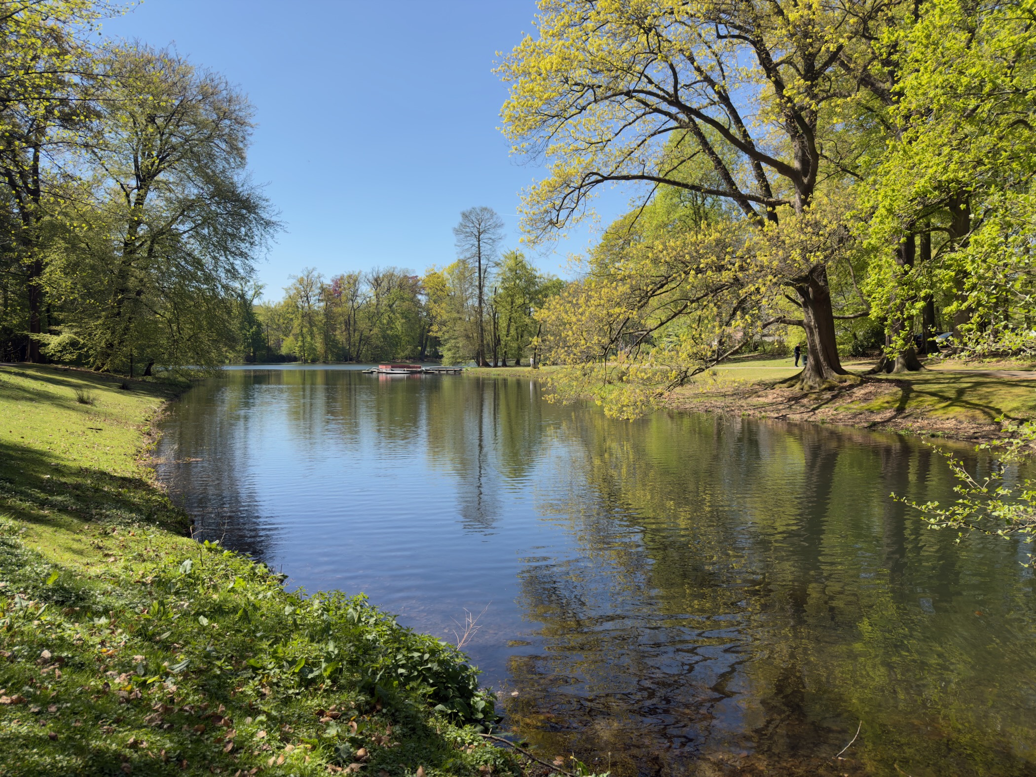 Reflective pond in Sonsbeek park with a small red pedal boat in the distance