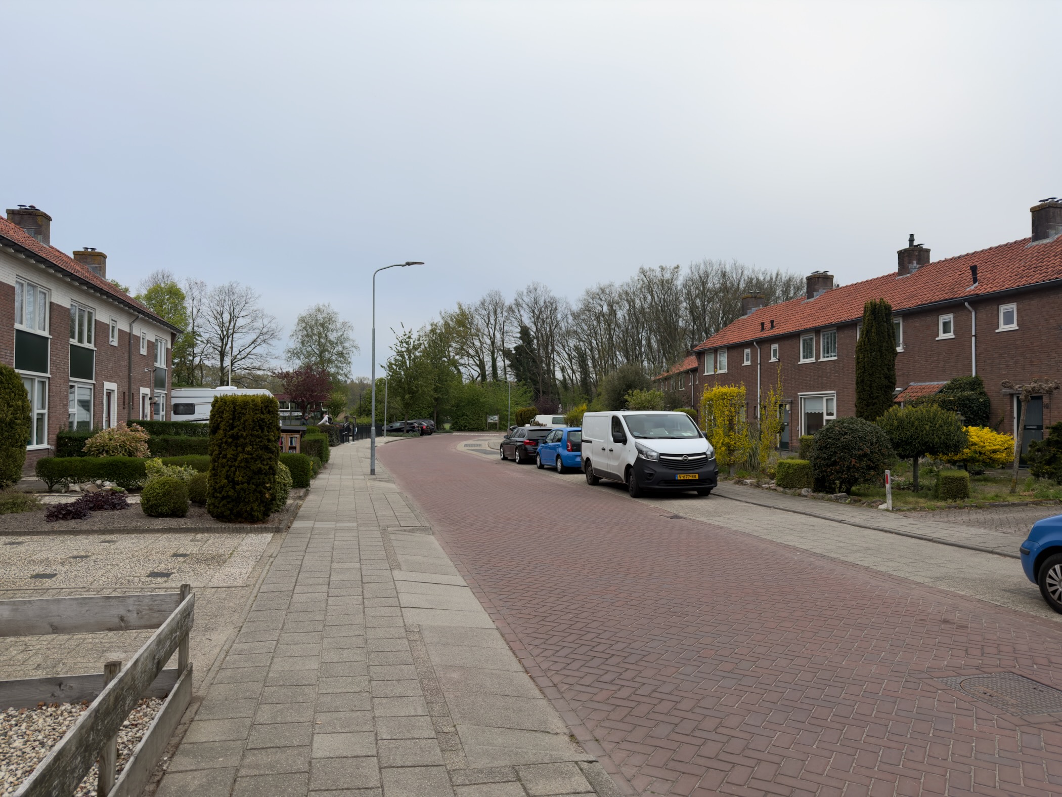 Quiet residential street with brick terraces and parked cars under an overcast sky