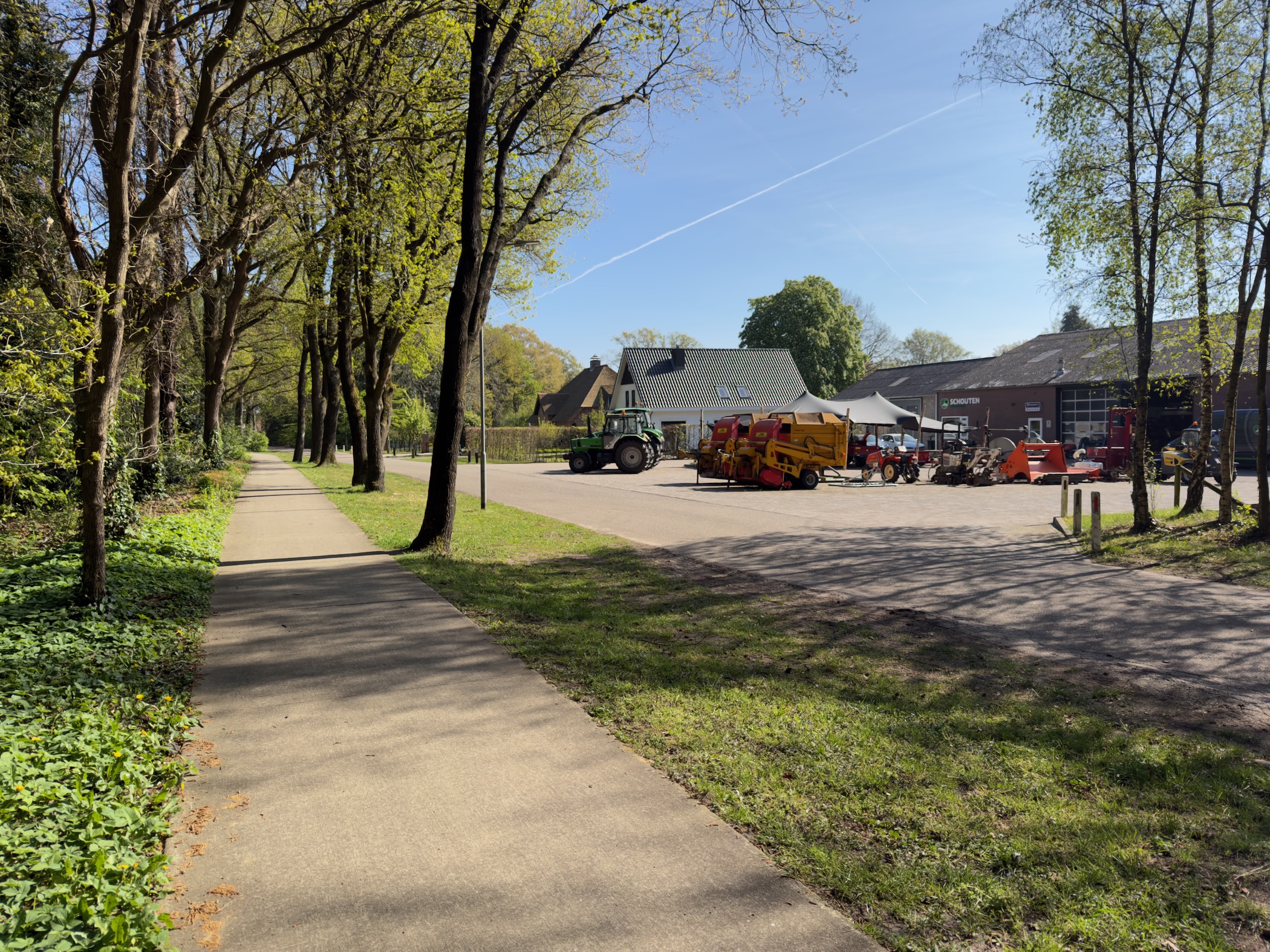 Farm yard with a tractor and machinery on a paved path beside outbuildings