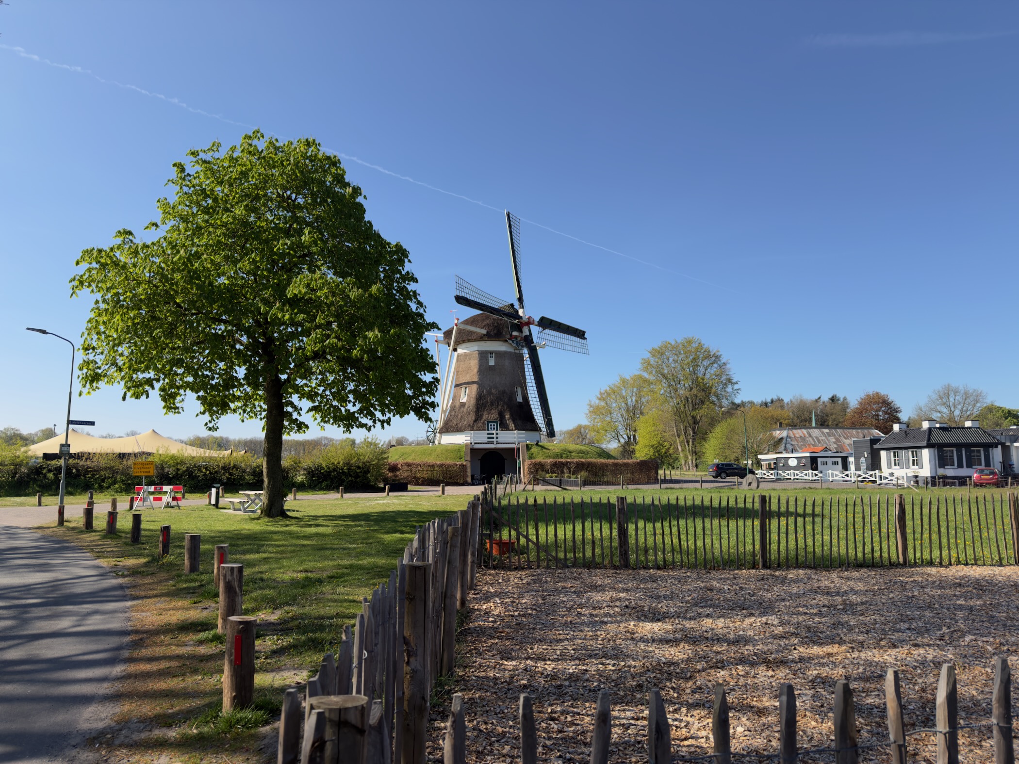 Traditional Dutch windmill beside a village green behind a wooden fence