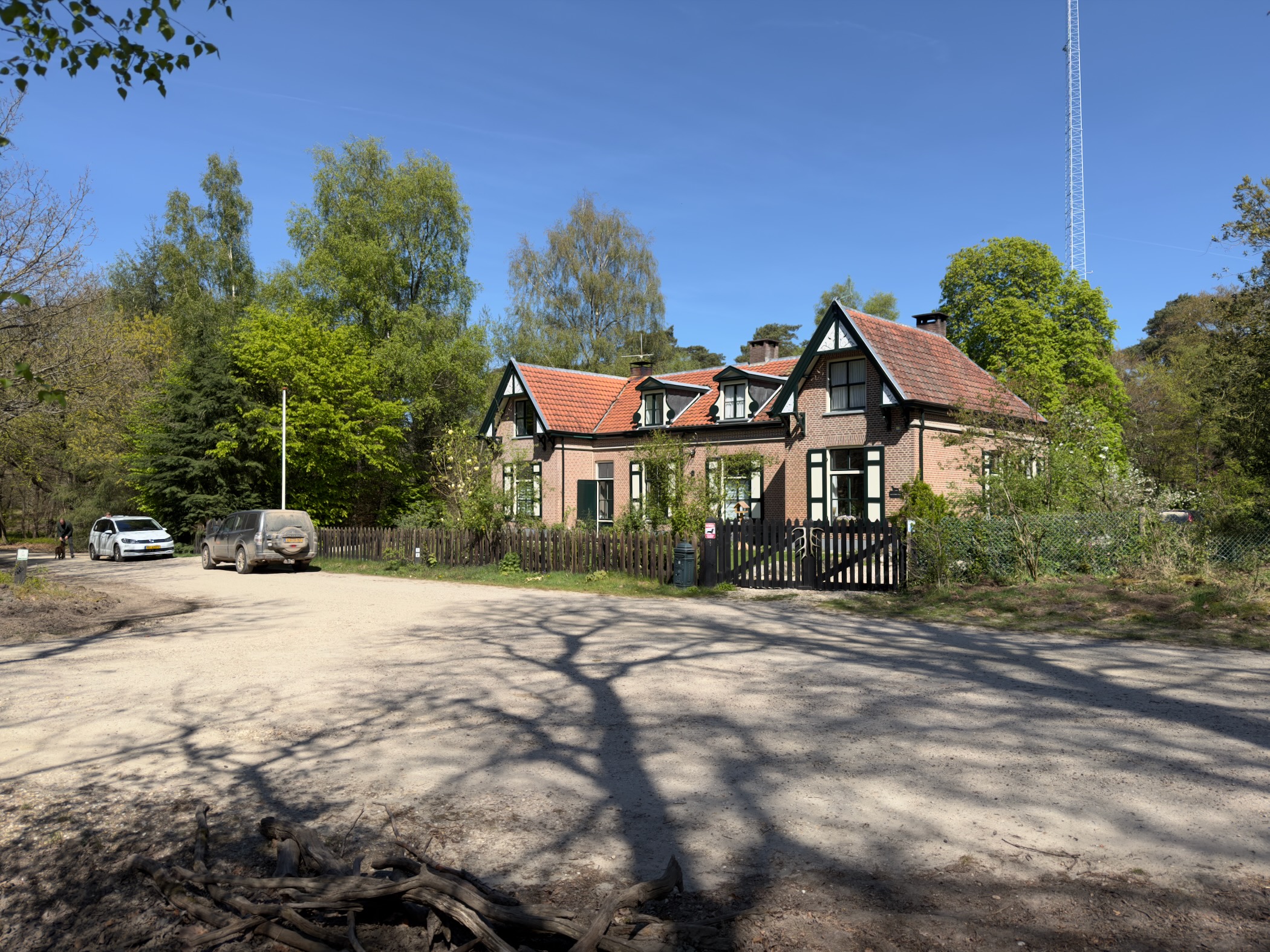 Clearing beside a brick lodge-style building with cars parked and a radio mast rising above