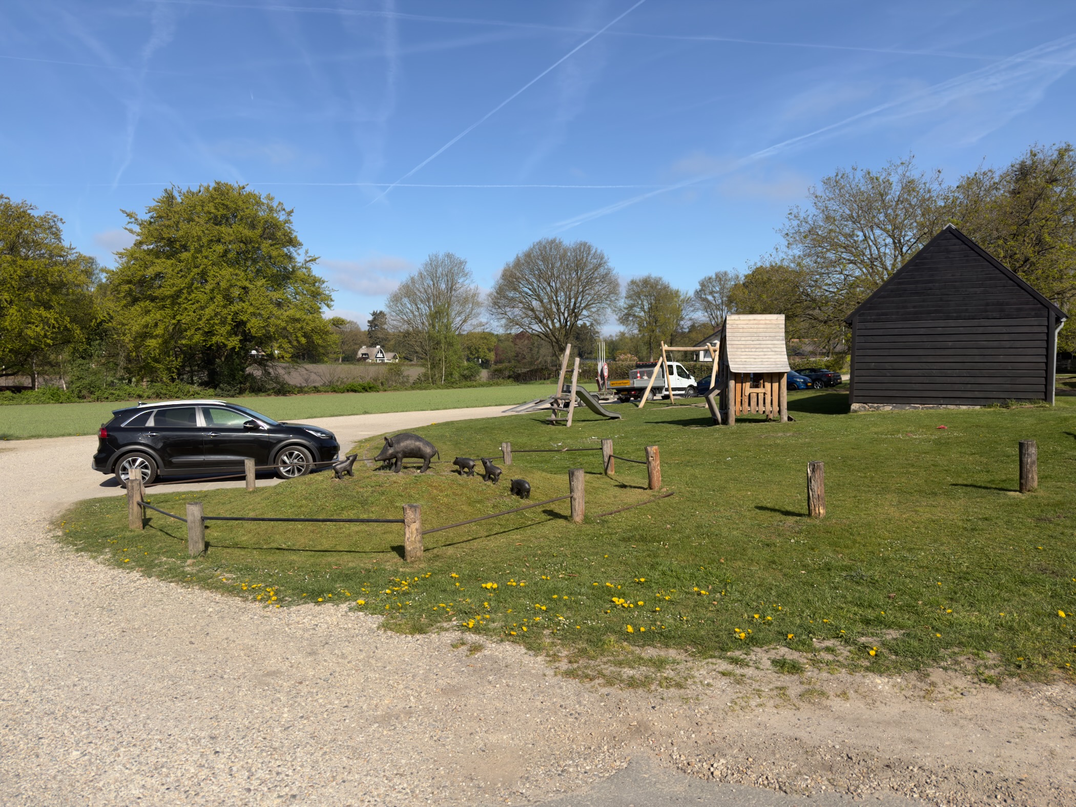 Car park at Hoog Soeren with a wooden barn and playground under a clear sky