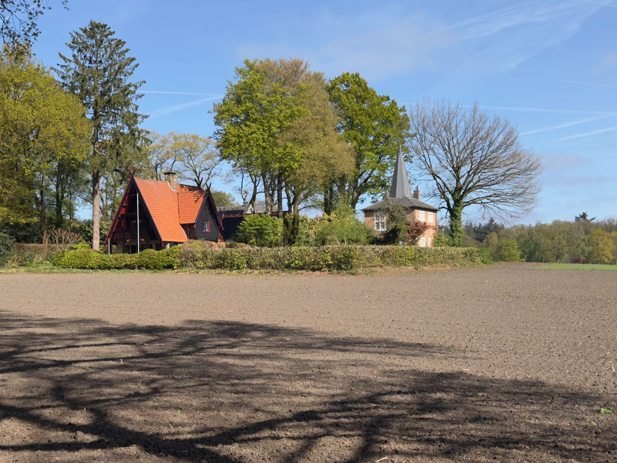 Red timber house and small tower seen over a ploughed field