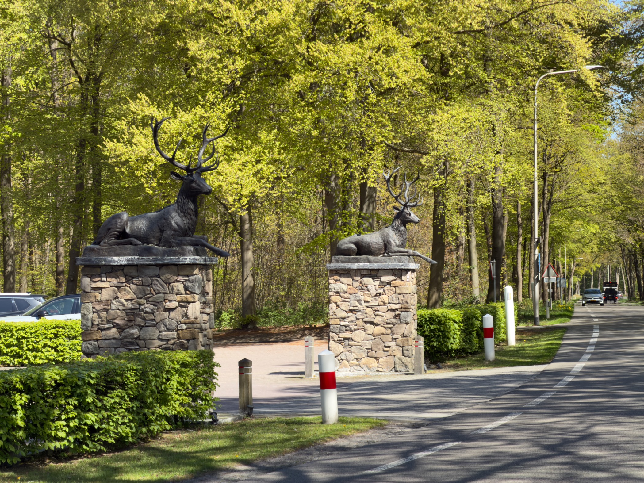 Stone gateposts topped with bronze stag statues at a road entrance