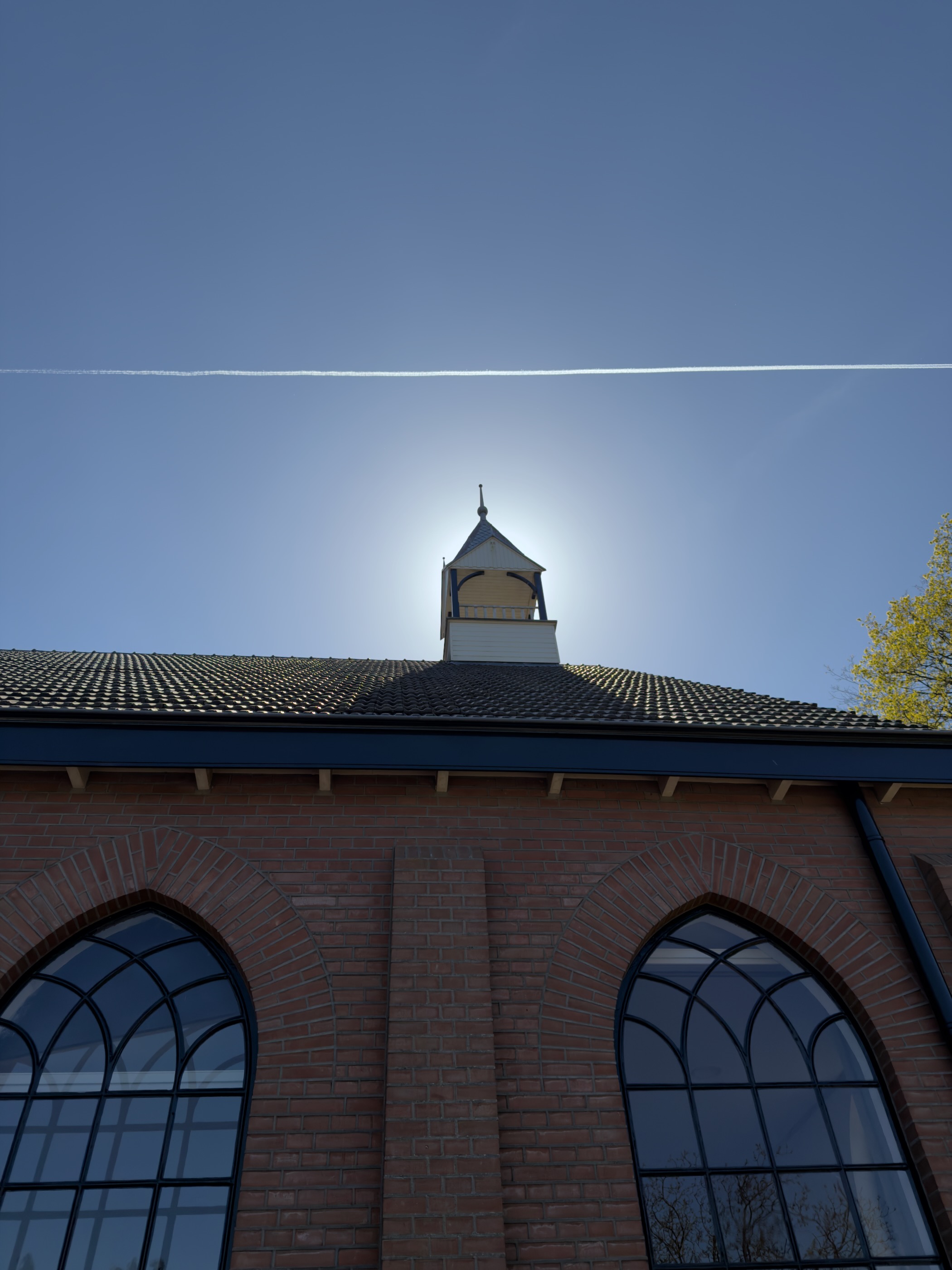 Small bell tower of a red brick chapel against the bright sky