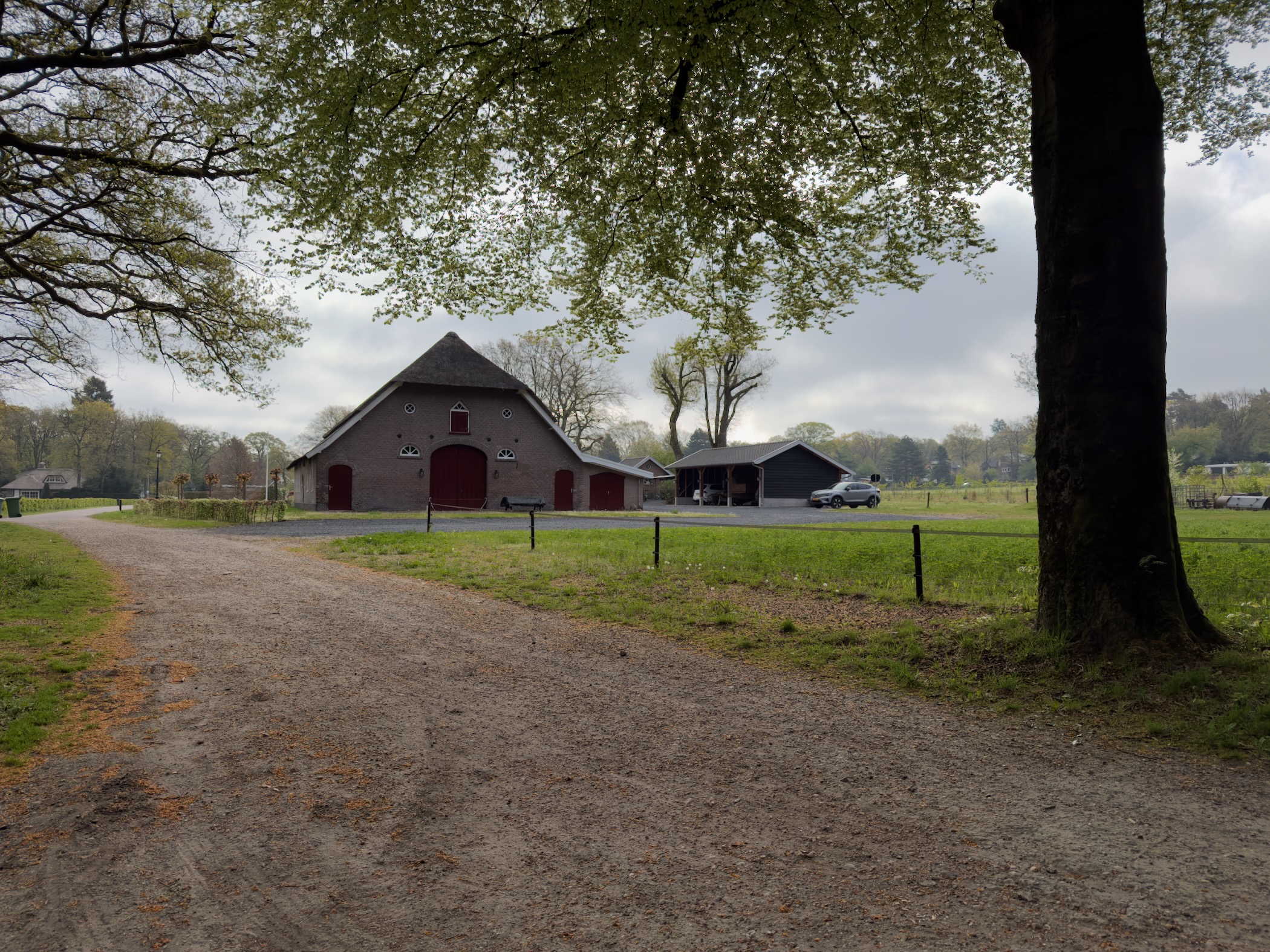 An old farm building with red doors under a cloudy sky
