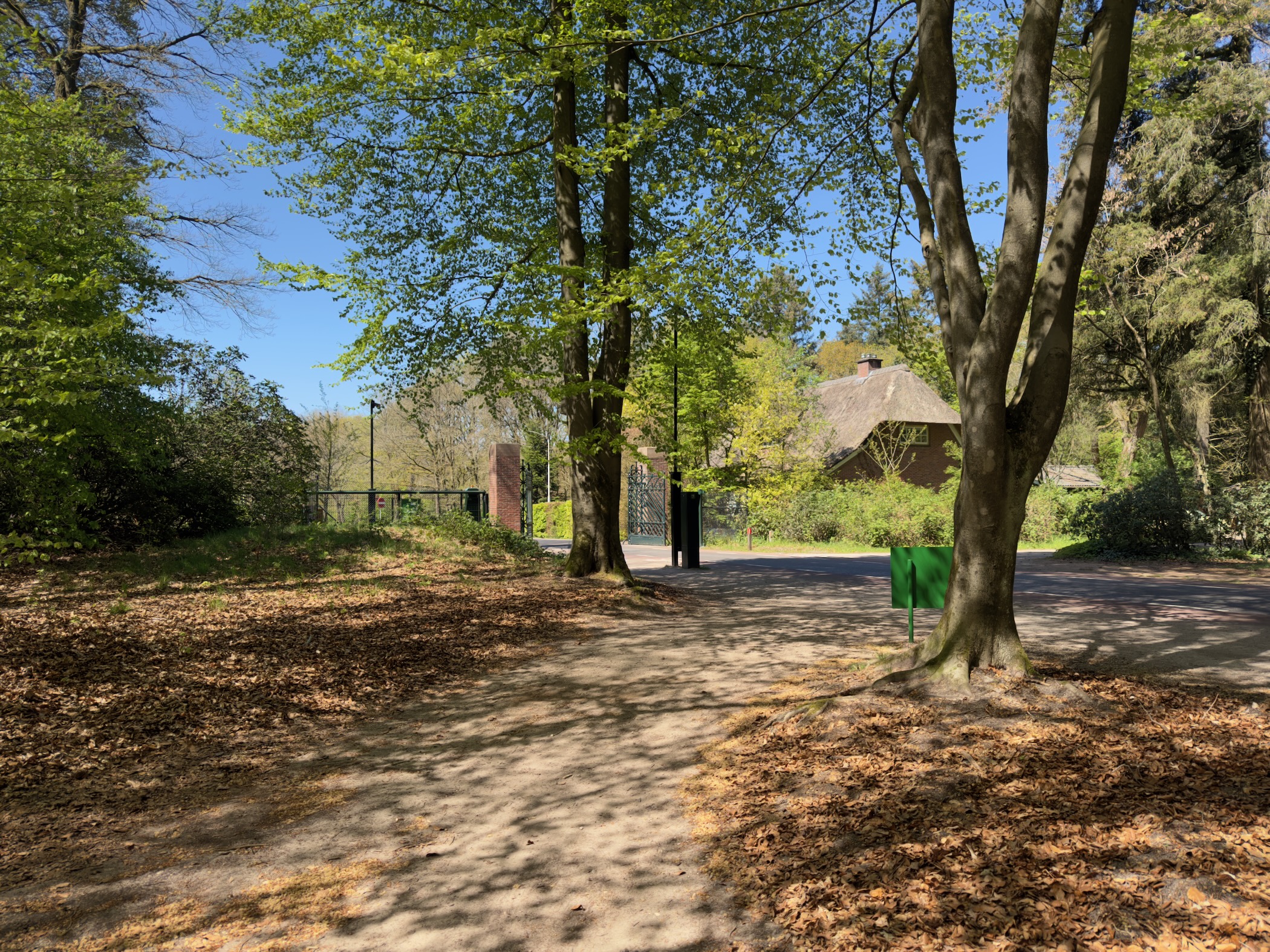 A park gate with a thatched roof house beyond