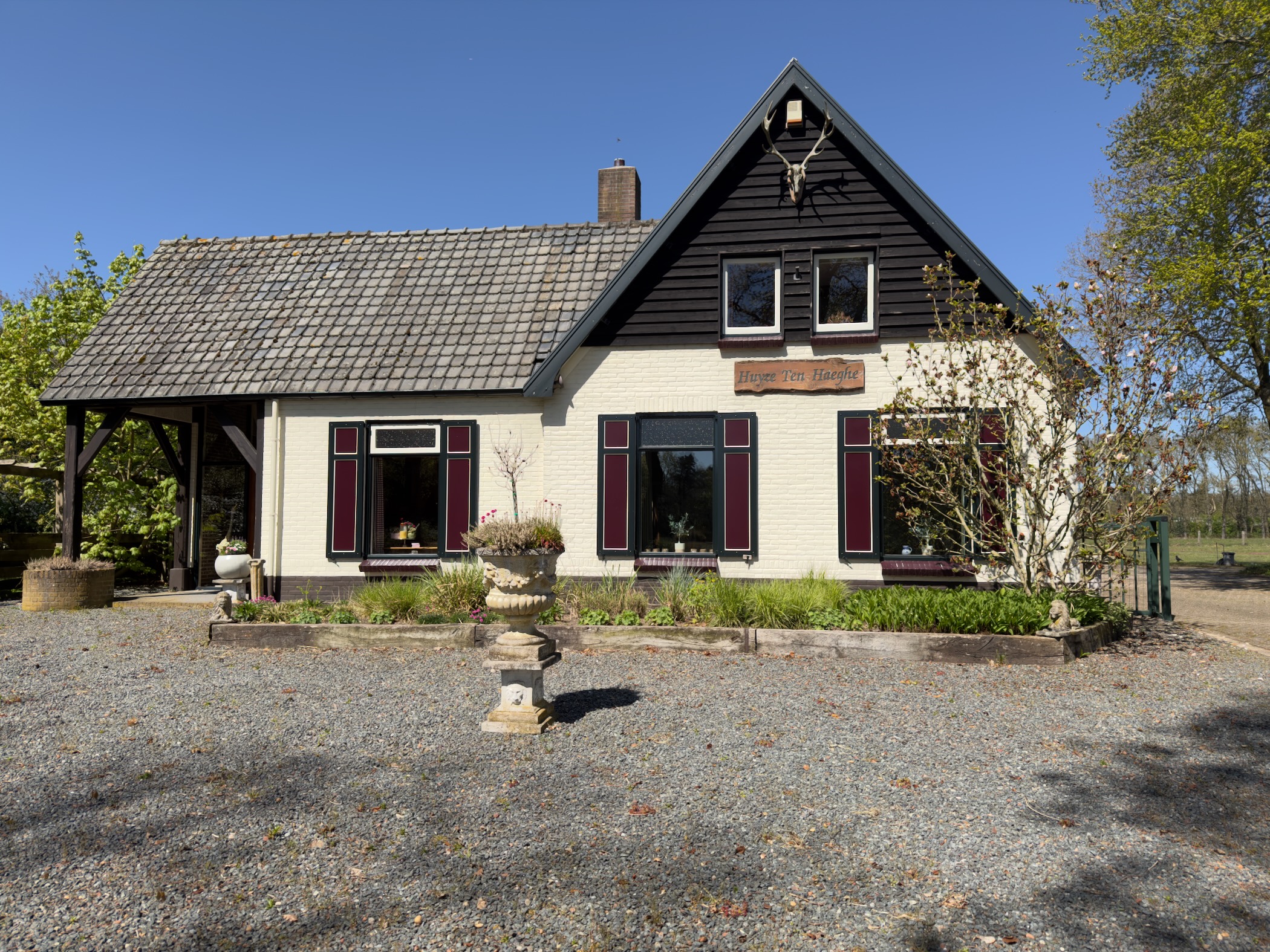 An old white farmhouse with dark red shutters