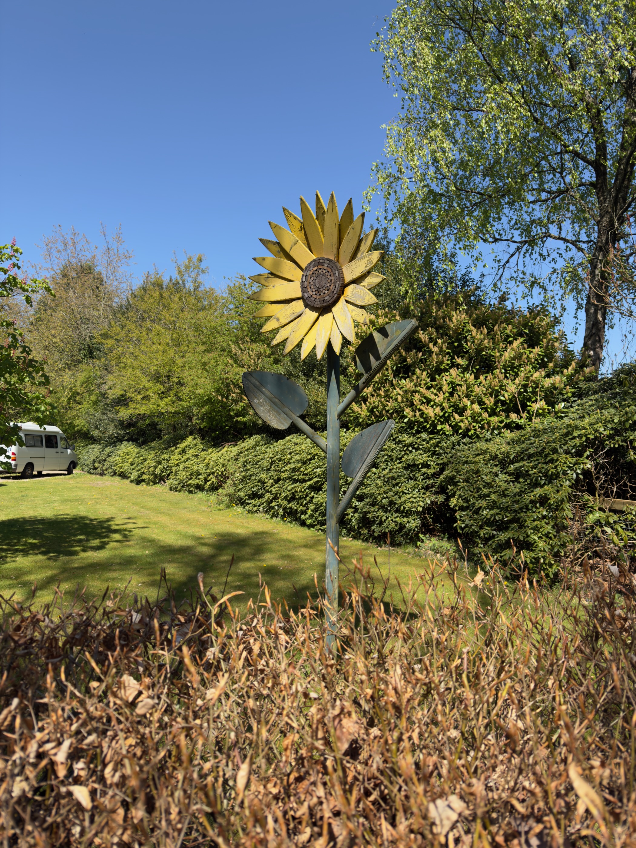 A tall metal sunflower sculpture standing in a garden