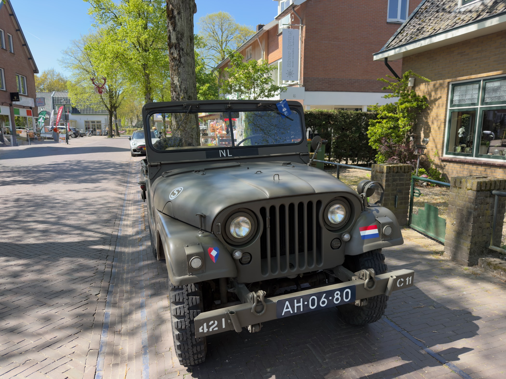 An old green military jeep parked on a street in Otterlo