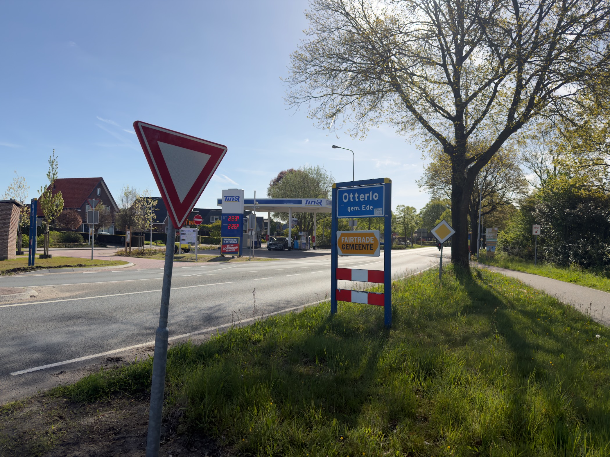 Otterlo town sign and yield sign by a roadside in spring