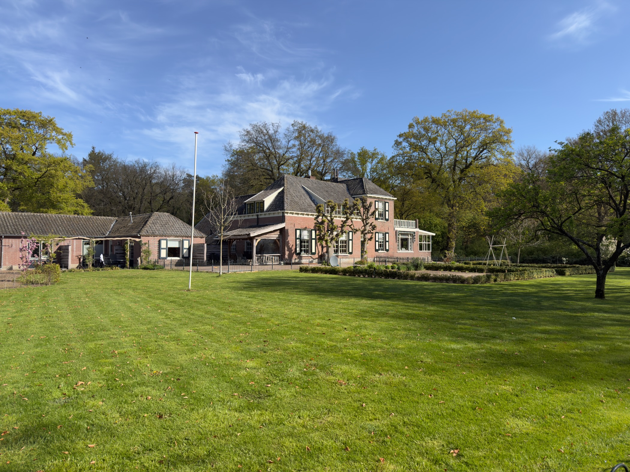 Brick farmhouse with a red roof on a wide green lawn